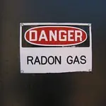Red and white warning sign reading "DANGER RADON GAS," indicating the presence of hazardous radon gas in the area. Important for safety awareness.