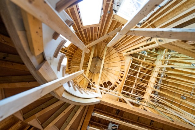Interior view of a spiral staircase under construction, showcasing wooden beams and circular design, highlighting architectural work in progress.