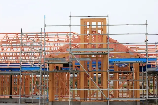New residential construction featuring wooden framing and scaffolding, highlighting the building process and structural elements.