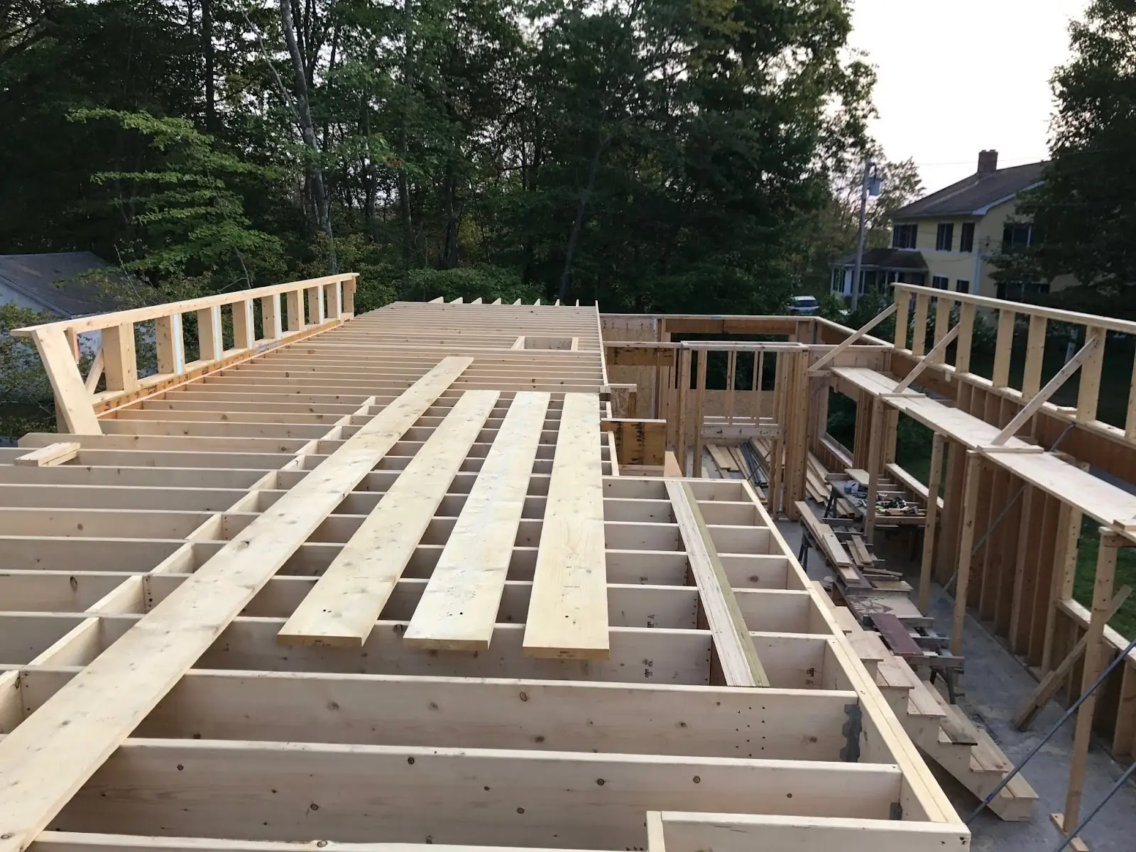 Construction site featuring a partially built wooden structure. Framing and planking are visible, showcasing the progress of the home under construction.